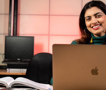 lady sat behind open laptop smiling to camera