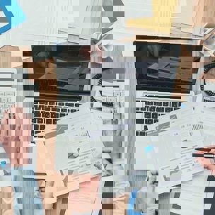 overview of people working at desk with laptop calculator and pages with numbers and charts on
