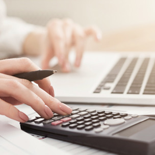 close up of person using calculator and laptop