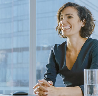 smiling woman sat assuredly talking at office desk